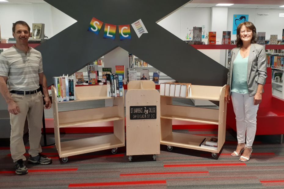 Professor Daniel Roy and carpentry student Natalie Mercier stand beside the three library carts made by students